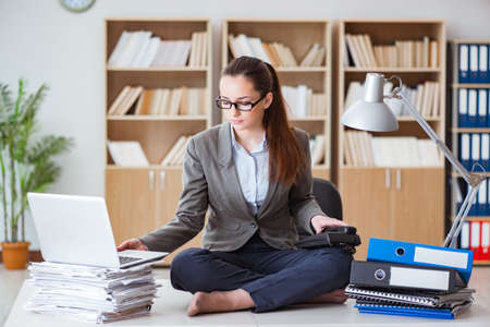 Busy angry businesswoman sitting on the desk in officeの写真素材