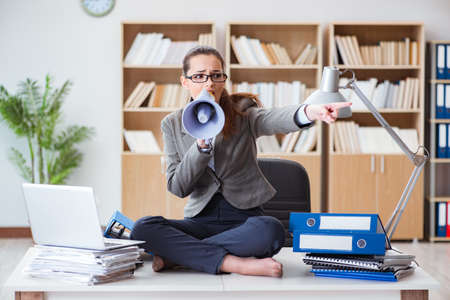 Businesswoman with loudspeaker in officeの写真素材
