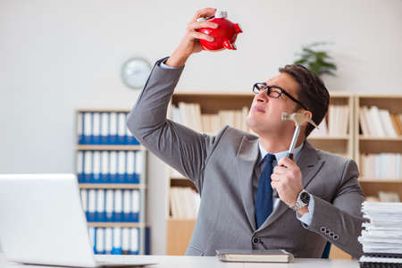 Businessman in search of his savings with piggy bankの写真素材