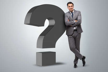 Businessman next to the giant question markの写真素材