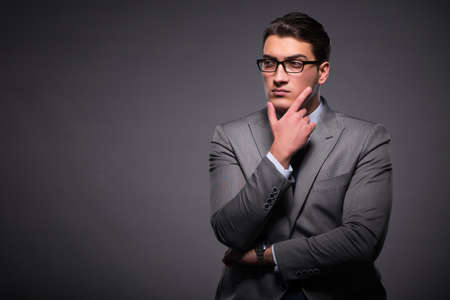 Handsome businessman against dark backgroundの写真素材