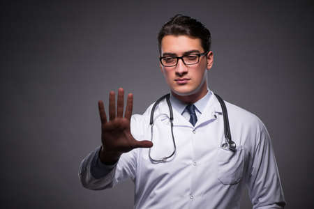 Young doctor against dark backgroundの写真素材