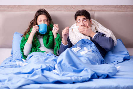 Sick wife and husband in bed in homeの写真素材