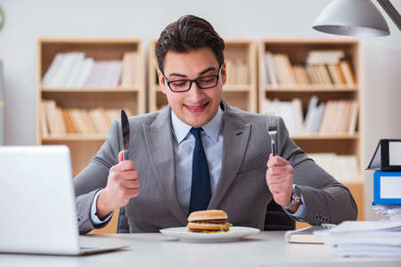 Hungry funny businessman eating junk food sandwichの写真素材
