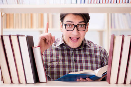 Young student looking for books in college libraryの写真素材