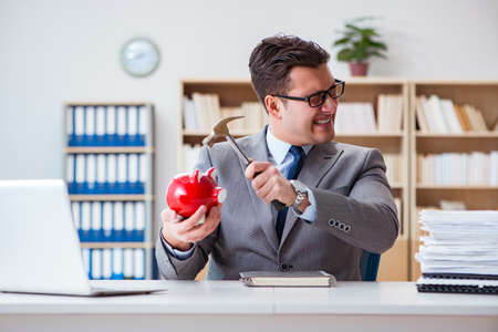 Businessman breaking piggybank in the officeの写真素材