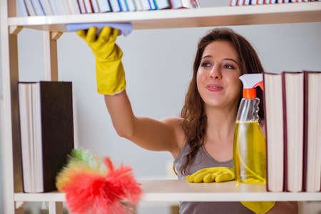 Woman cleaning dust from bookshelf