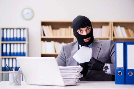 Criminal businessman with balaclava in officeの写真素材