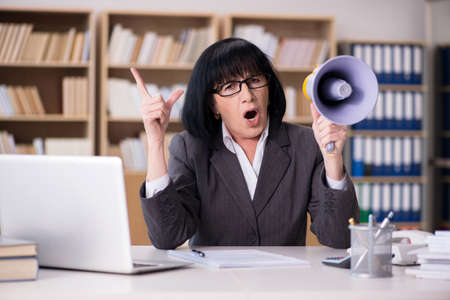 Angry businesswoman shouting with loudspeakerの写真素材