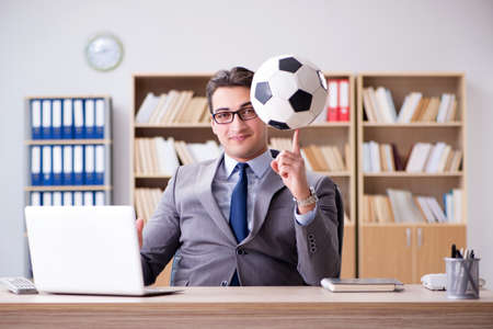 Businessman with football ball in officeの写真素材