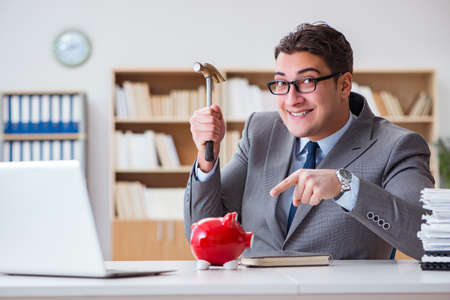 Businessman breaking piggybank in the officeの写真素材