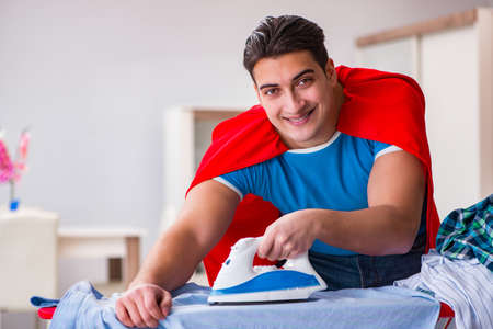 Super hero man husband ironing at homeの写真素材