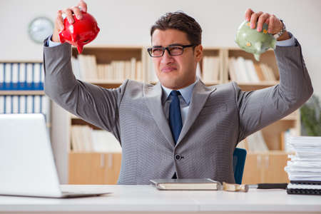 Businessman in search of his savings with piggy bankの写真素材