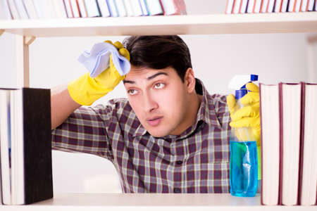 Man cleaning dust from bookshelfの写真素材