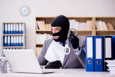 Criminal businessman with balaclava in office