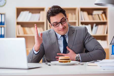Hungry funny businessman eating junk food sandwichの写真素材