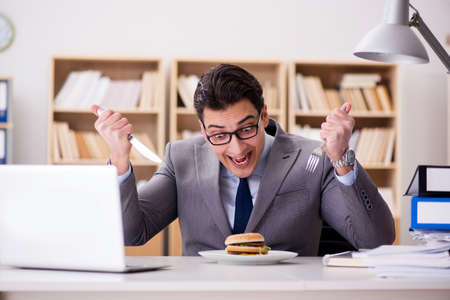 Hungry funny businessman eating junk food sandwichの写真素材