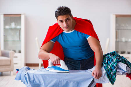 Super hero man husband ironing at homeの写真素材