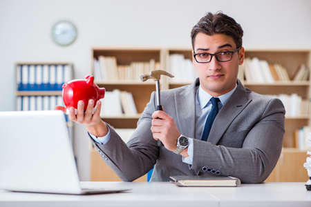 Businessman breaking piggybank in the officeの写真素材