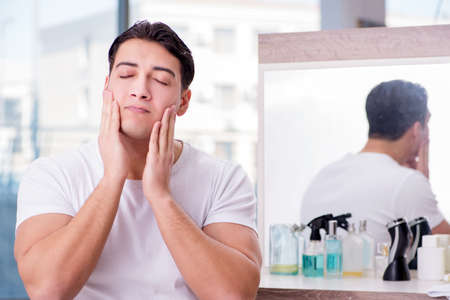 Young handsome man applying face creamの写真素材