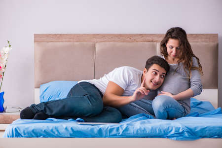 Young family with pregnant wife expecting baby in bedの写真素材