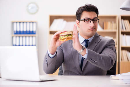 Hungry funny businessman eating junk food sandwichの写真素材