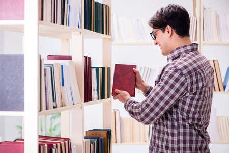Young student looking for books in college library