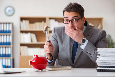 Businessman in search of his savings with piggy bankの写真素材