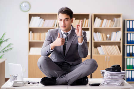 Young businessman meditating in the officeの写真素材
