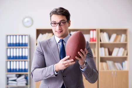 Businessman with american football in officeの写真素材