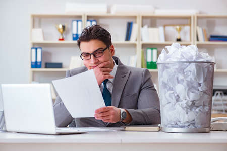 Businessman in paper recycling concept in officeの写真素材