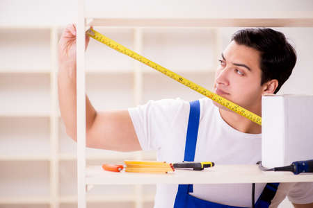 Worker man repairing assembling bookshelfの写真素材