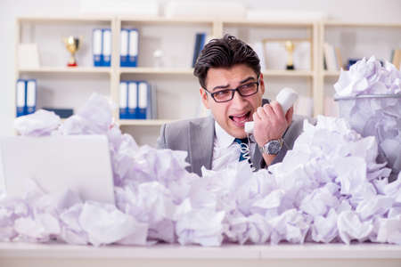 Businessman in paper recycling concept in officeの写真素材