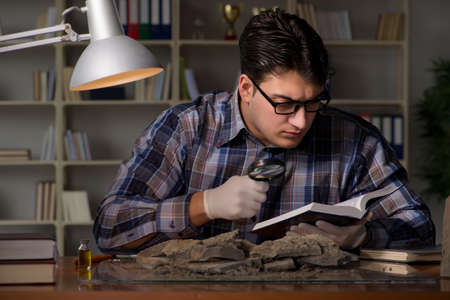 Archeologist working late night in officeの写真素材