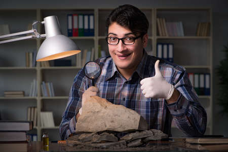 Archeologist working late night in officeの写真素材