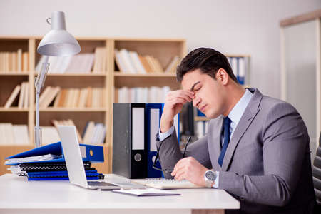 Sleepy businessman working in officeの写真素材