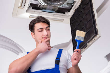 Worker repairing ceiling air conditioning unitの写真素材