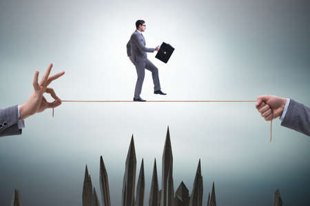 Businessman walking on tight rope in business conceptの写真素材