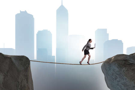 Businesswoman walking on tight rop in business conceptの写真素材