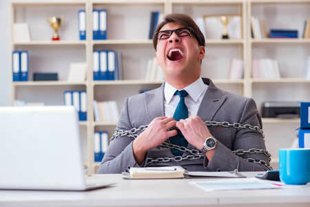 Businessman tied with chains to his workの写真素材