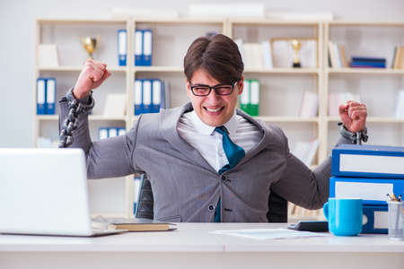 Businessman tied with chains to his workの写真素材