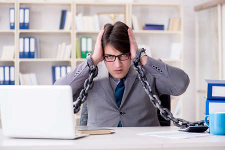 Businessman tied with chains to his workの写真素材