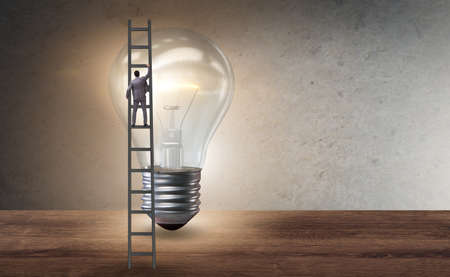 Businessman on ladder with light bulbの写真素材