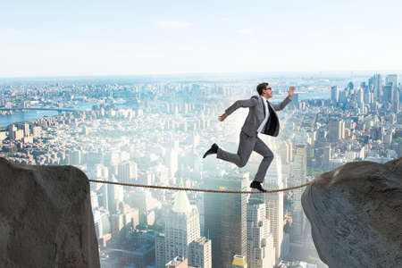 Businessman walking on tight rop in business conceptの写真素材