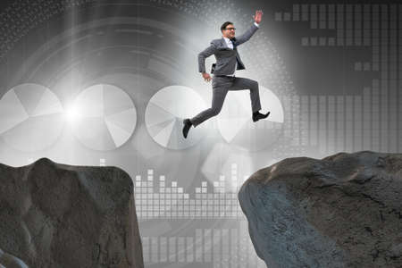 Ambitious businessman jumping over the cliffの写真素材