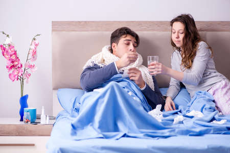 Wife caring for sick husband at home in bedの写真素材