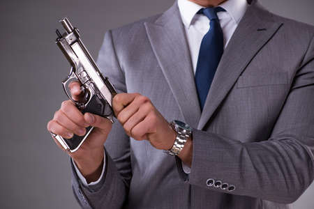 Businessman pulling the gun out of pocketの写真素材