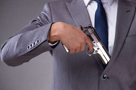 Businessman pulling the gun out of pocket