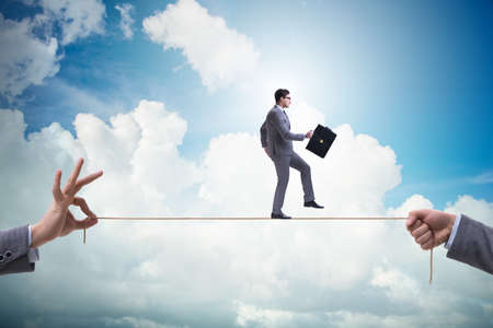 Businessman walking on tight rope in business conceptの写真素材