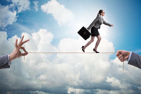 Businesswoman walking on tight rope in business conceptの写真素材